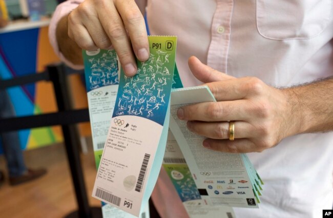 FILE - In this June 20, 2016, file photo, a man handles the Olympic tickets he just purchased at a shopping mall in Rio de Janeiro, Brazil. Tokyo Olympic organizers launched their ticket website on Thursday, April 18, 2019.