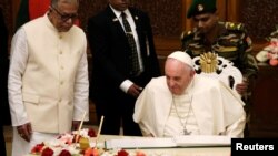 Bangladesh's President Abdul Hamid watches as Pope Francis writes in a book at the presidential palace in Dhaka, Bangladesh, Nov. 30, 2017. 