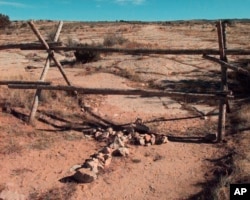 FILE - A cross made of stones rests below the fence in Laramie, Wyo., Oct. 9, 1999, where a year earlier University of Wyoming student Matthew Shepard was tied and pistol whipped into a coma. The murder of Shepard was a watershed moment for gay rights and LGBTQ acceptance in the U.S., so much so that 20 years later the crime remains seared into the national consciousness.