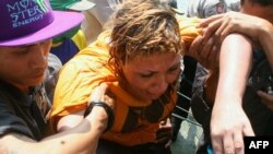 A survivor, centers, is given assistance as a search and rescue operation continues in Cidaun, West Java, after an Australia-bound boat sank off the Indonesian coast, July 24, 2013.