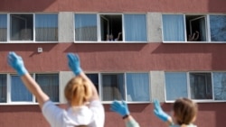 Residents of a nursing home enjoy as the MAV Symphony Orchestra plays classical music recordings on loudspeakers of a car going around the city to cheer up people under lockdown, during the coronavirus disease (COVID-19) outbreak in Budapest, Hungary, April 7, 2020. (REUTERS/Bernadett Szabo)