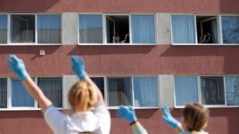 Residents of a nursing home enjoy as the MAV Symphony Orchestra plays classical music recordings on loudspeakers of a car going around the city to cheer up people under lockdown, during the coronavirus disease (COVID-19) outbreak in Budapest, Hungary, April 7, 2020. (REUTERS/Bernadett Szabo)