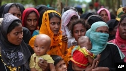 Rohingya women carry children and wait for food handouts at Thangkhali refugee camp in Cox's Bazar, Bangladesh, Oct. 5, 2017.