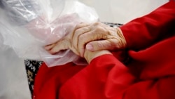 Gregg MacDonald holds hands with his 84-year-old mother, Chloe MacDonald, at a "hug tent" set up outside the Juniper Village assisted living center in Louisville, Colorado, on Wednesday, Feb. 3, 2021. (AP Photo/Thomas Peipert)