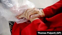 Gregg MacDonald holds hands with his 84-year-old mother, Chloe MacDonald, at a "hug tent" set up outside the Juniper Village assisted living center in Louisville, Colorado, on Wednesday, Feb. 3, 2021. (AP Photo/Thomas Peipert)