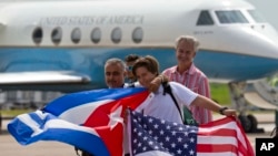 Passengers of JetBlue flight 387 holding a United States, and Cuban national flags, pose for photos in front of the plane transporting U.S. Transportation Secretary Anthony Foxx, at the airport in Santa Clara, Cuba, Aug. 31, 2016