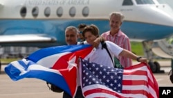 Para penumpang pesawat Jet Blue nomor penerbangan 387 mengibarkan bendera Kuba dan AS usai mendarat di Santa Clara, Kuba, Rabu (31/8). 