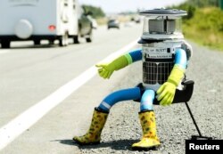 The anthropomorphic robot named hitchBOT sits on the shoulder of Highway 102 to begin its 6000 kilometer cross country journey outside of Halifax, Nova Scotia, July 27, 2014.