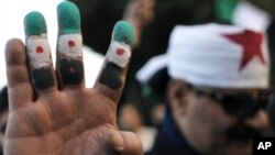 An anti-Syrian regime protester colors his fingers with the revolutionary flag colors during a protest outside the Arab League headquarters in Cairo, Egypt Sunday, Jan. 22, 2012.