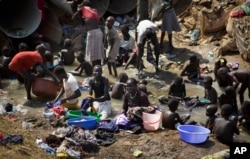 FILE - Displaced people bathe and wash clothes in a stream inside a United Nations compound which has become home to thousands of people displaced by the recent fighting, in Juba, South Sudan, Dec. 27 , 2013.