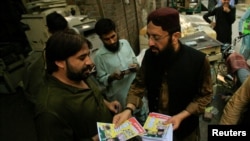 FILE - Mohammad Yaqoob Sheikh, right, nominated candidate of the Milli Muslim League, distributes handbills to residents during an election campaign for the National Assembly NA-120 constituency in Lahore, Pakistan, Sept. 10, 2017.