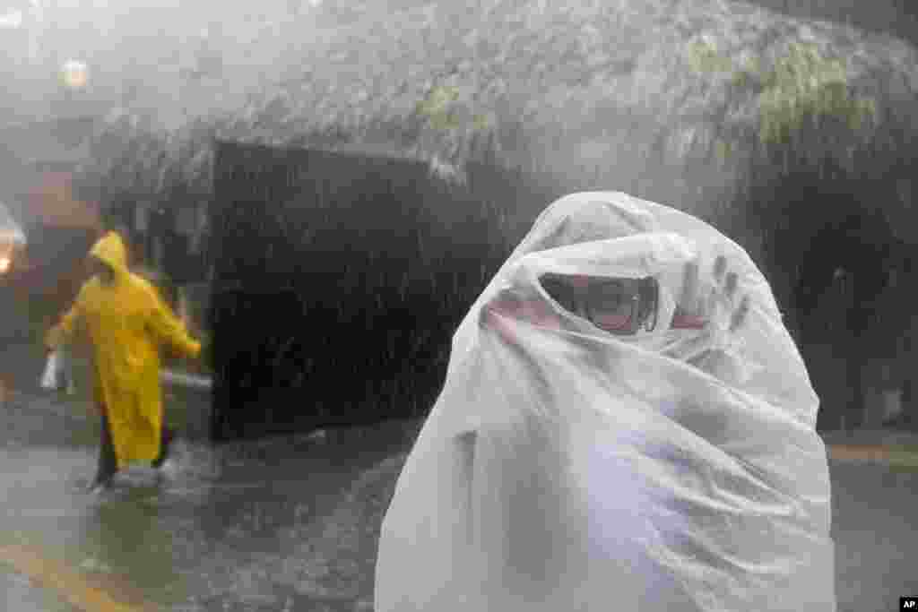 زنی با پوشیدن کیسه بزرگ پلاستیکی خود را از بارانهای توفان ماریا در دومینیکن محفوظ نگه داشته است.