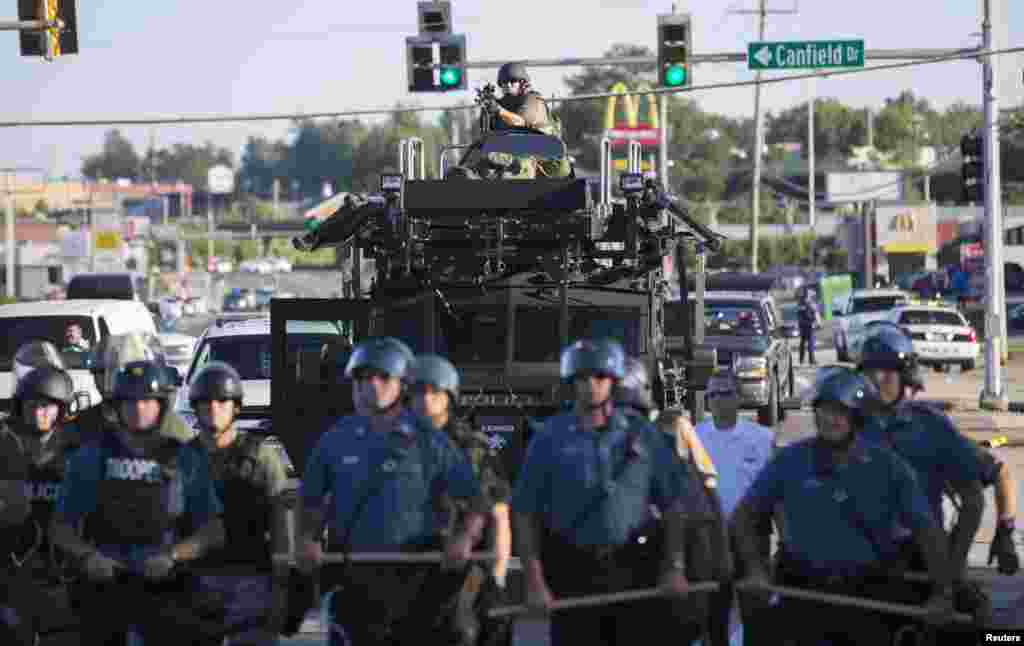 Polícia de choque americana de guarda, enquanto os manifestantes protestam contra a morte a tiro do jovem de 18 anos, Michael Brown, em Ferguson, Missouri Ago. 13, 2014.