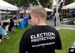 FILE - Lisa Hubbard, a volunteer with the non-partisan Election Protection Coalition, attends an early voting celebration outside of Jackson Memorial Hospital, on the first day of early voting in Miami-Dade County for the general election in Miami, Oct. 24, 2016. OAS and OSCE observers will participate in the U.S. election.