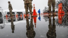 National Guard personnel stand at attention as they wait for patients to arrive for COVID-19 coronavirus testing facility at Glen Island Park, in New Rochelle, N.Y.