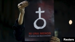 FILE - A woman holds up a poster with female symbol during a demonstration demanding policies to prevent femicides in Buenos Aires, Argentina, June 3, 2015. 