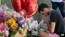 Paolo Singer, 27, a Silver Lake resident, prays at a makeshift memorial of flowers, candles and notes on the sidewalk outside the Silver Lake Trader Joe's store in Los Angeles, July 23, 2018. Trader Joe's employee Melyda Corado was shot and killed at the store in a gunfight Saturday between a gunman and police. 