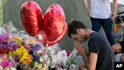 Paolo Singer, de 27 años, residente de Silver Lake, reza en una improvisado altar de flores, velas y notas en la acera frente a la tienda Trader Joe's en Silver Lake, en Los Ángeles, el 23 de julio de 2018.