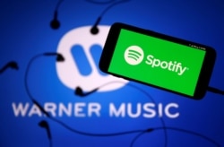 Layanan streaming musik "Spotify" dan logo label "Warner Music". (Foto: ilustrasi).