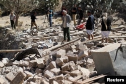 People walk on the rubble of a house destroyed by a Saudi-led airstrike in Sana'a, Yemen, Feb. 2, 2017.
