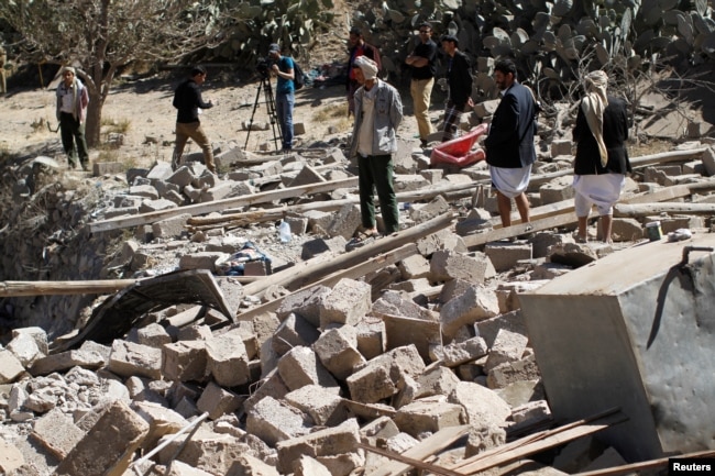 People walk on the rubble of a house destroyed by a Saudi-led airstrike in Sana'a, Yemen, Feb. 2, 2017.