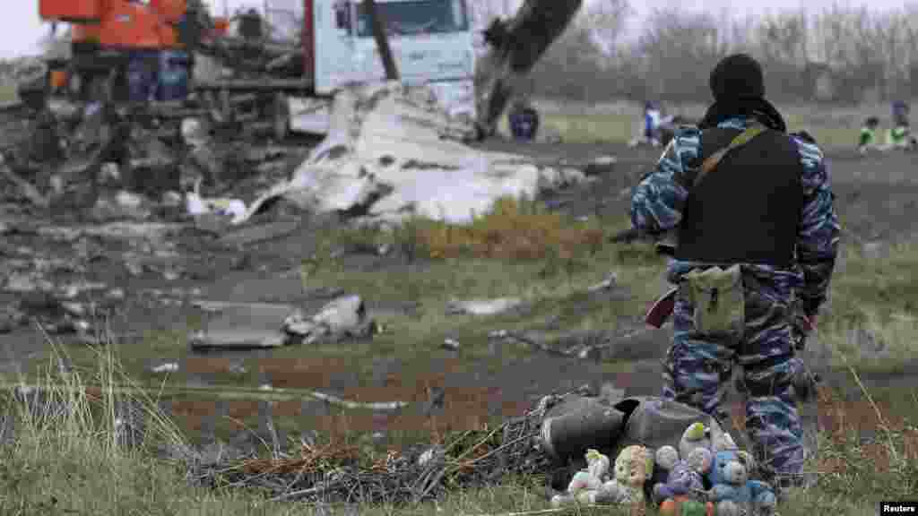 Un homme armé pro-russe, avec un tas d&#39;animaux en peluche à ses pieds, sécurise le site de l&#39;accident d&#39;avion de Malaysia Airlines MH17 près de la colonie de Grabovo dans la région de Donetsk, le 16 novembre 2014.