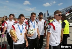 German soccer players Miroslav Klose, Philipp Lahm, Lars Bender, Sami Khedira and Toni Kroos (L-R) walk with the World Cup trophy at Tegel airport in Berlin, July 15, 2014.