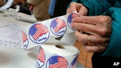 A voter retrieves her "I Voted" sticker after casting her ballot at the Presbyterian Church of Mount Kisco, in Mt. Kisco, N.Y. Tuesday, Nov. 6, 2018. 