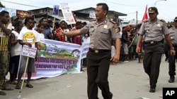 Policemen walk in front of demonstrators during a rally outside the local parliament in Abepura, Jayapura, Indonesia's Papua province, August 2, 2011