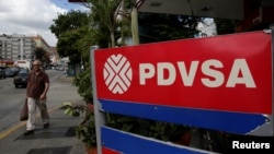 FILE - A man walks past the corporate logo of the state oil company PDVSA at a gas station in Caracas, Venezuela, Dec. 1, 2017. 