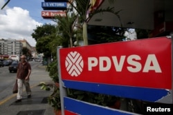 FILE - A man walks past the corporate logo of the state oil company PDVSA at a gas station in Caracas, Venezuela, Dec. 1, 2017.