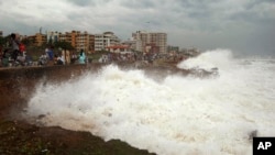 Indian people watch high tide waves as they stand at the Bay of Bengal coast in Vishakhapatnam, India, Oct. 12, 2013. 