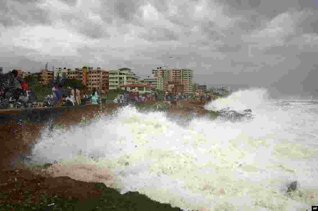 Indian people watch high tide waves as they stand at the Bay of Bengal coast in Vishakhapatnam. Hundreds of thousands of people living along the eastern coastline were taking shelter from a massive, powerful cyclone Phailin.
