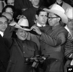 歷史照片：在德克薩斯州西蒙頓的牛仔競技場上，一名助手幫助中國國務院副總理鄧小平試戴一頂牛仔帽。 (1979年2月2日)