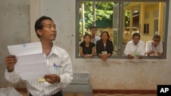 An election worker calls votes off a ballot as election observers look on through a window, (file photo). 