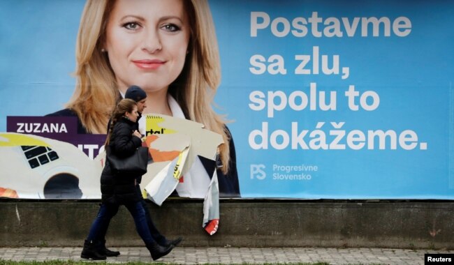 People walk past an election poster of Slovakian presidential candidate Zuzana Caputova in Bratislava, Slovakia, March 15, 2019. The poster reads: "President for fair Slovakia. Stand up against evil, together we can do it."
