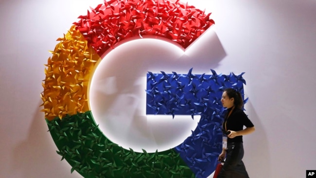 In this Monday, Nov. 5, 2018 file photo, a woman walks past the logo for Google at the China International Import Expo in Shanghai. (AP Photo/Ng Han Guan, File)