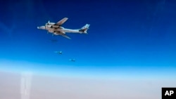 In this photo made from the footage taken from Russian Defense Ministry official web site on Wednesday, July 5, 2017 Russian strategic T-95 bomber, with Russian jet fighters at rear, launches X-101 cruise missiles on IS facilities in the area along the boundary between the provinces of Hama and Homs in Syria.