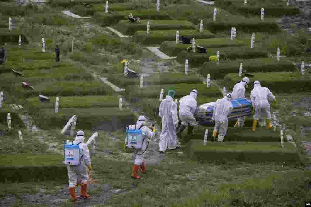 Workers in protective suits carry a coffin containing the body of a person who presumably died of the coronavirus for burial in Medan, North Sumatra, Indonesia.