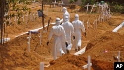 Health workers walk inside a new graveyard as they move bury people suspected of dying from the Ebola virus on the outskirts of Monrovia, Liberia, Wednesday, March 11, 2015. Liberians held a church service Wednesday for families who lost members to Ebola to mark the country’s 99th celebration National Decoration Day, a holiday normally set aside for people to clean up and re-decorate the graves of their lost relatives. (AP Photo/Abbas Dulleh)