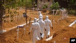 FILE - Health workers walk inside a new graveyard as they move bury people suspected of dying from the Ebola virus on the outskirts of Monrovia, Liberia, March 11, 2015. 