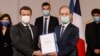 Le président français Emmanuel Macron détient conjointement un document aux côtés de l'historien Vincent Duclert, qui dirige la commission rwandaise à la salle des fêtes de l'Elysée à Paris, le 26 mars 2021.