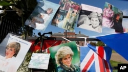 FILE - Pictures and flags marking the 20th anniversary of the death of Diana, Princess of Wales, hang on the gates of Kensington Palace in London, Aug. 31, 2017. 
