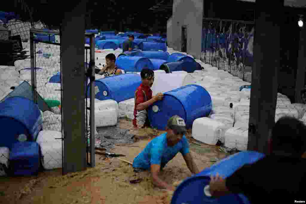 Men recover plastic barrels from a business affected by a flooding caused by rains from Storm Eta, in Toyos, Honduras, Nov. 4, 2020.