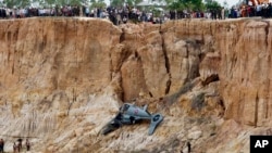 Soldiers use a crane to lift an aft section of a helicopter retrieved from a pond following its crash in Prey Sar village at the outskirt of Phnom Penh, Cambodia, Monday, July 14, 2014. The chopper went down about 10 kilometers (6 miles) south of Phnom Penh on Monday, sinking in a muddy pond surrounded by rural land and rice fields. (AP Photo/Heng Sinith)