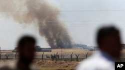 In this photo taken from the Turkish side of the border between Turkey and Syria, in Akcakale, southeastern Turkey, people watch as smoke from a U.S.-led airstrike rises over the outskirts of Tal Abyad, Syria, June 15, 2015. 