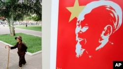 An elderly Vietnamese woman takes a morning walk in a park near a portrait of former communist leader Ho Chi Minh in Ho Chi Minh city