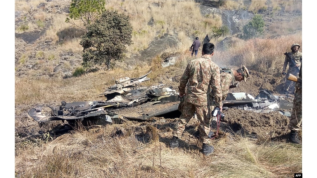 پاکستانی فوجی بھارتی فضایہ کے جنگی طیارے کے ملبے کے گرد جمع ہیں