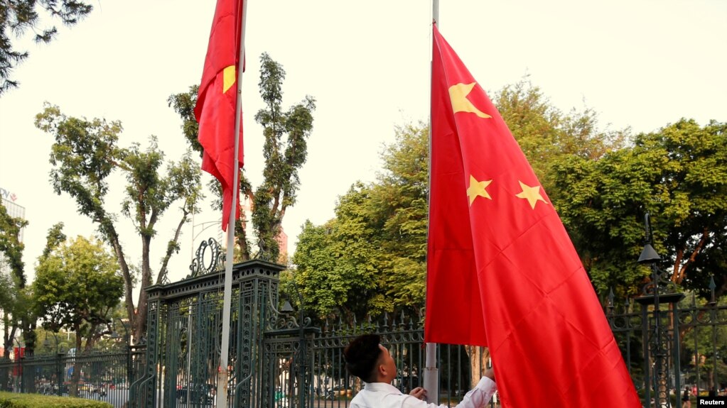 资料照：中越外长在河内举行会谈前，一名男子在越南政府办公机构前竖起的越南国旗旁升起中国国旗。（2017年11月2日）(photo:VOA)