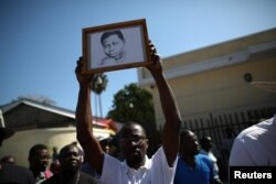 A man shows a portrait of missing local, freelance photojournalist Vladjimir Legagneur, during a march to demand information about his whereabouts, in Port-au-Prince, Haiti, March 28, 2018.